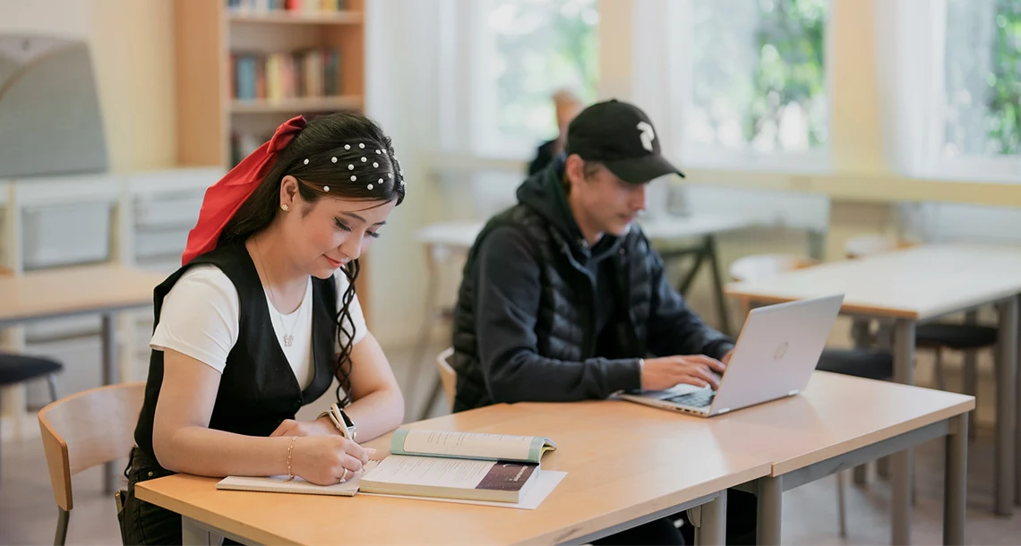 Två elever studerar i klassrumsmiljö.