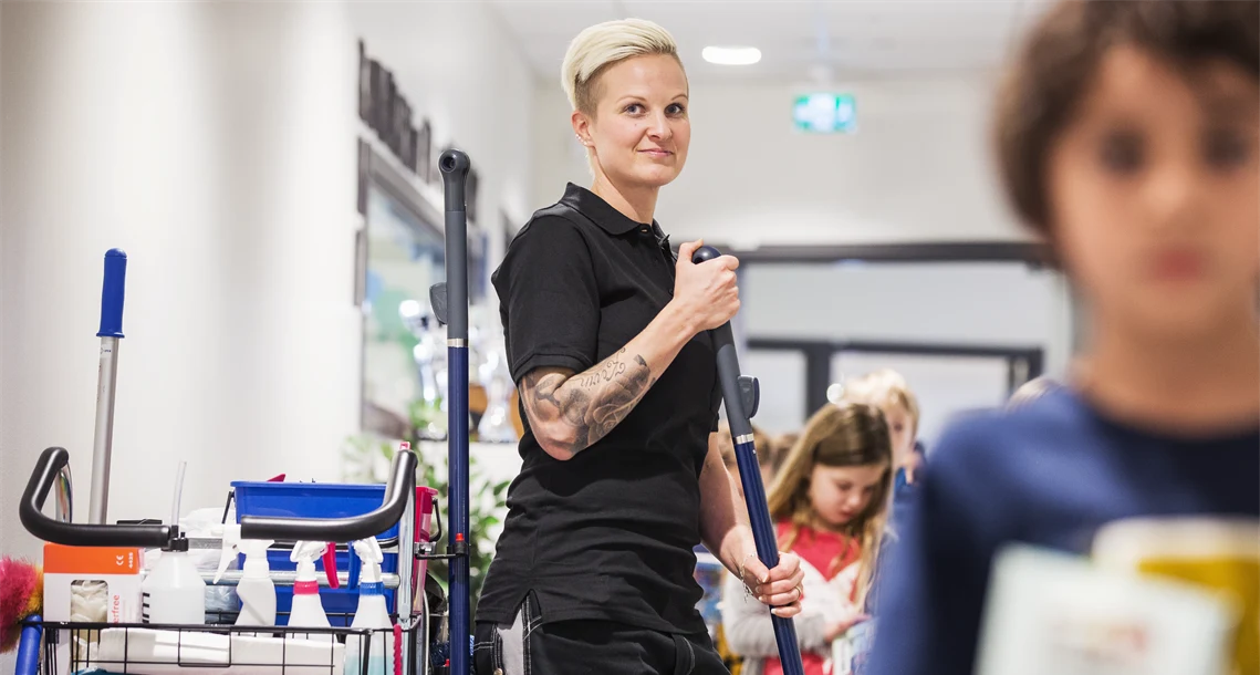 Städare står intill sin vagn med utrustning i korridor där elever går förbi
