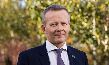 Man står utomhus och ler mot kameran
