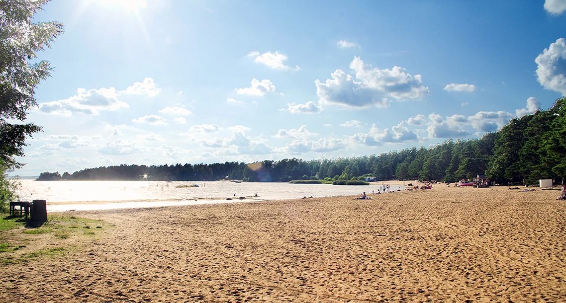 Sandstrand i motljus och blå himmel