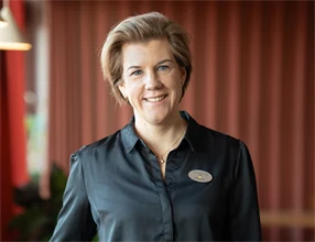 Porträtt av Linda Andersson Falk mot röd tyggardin