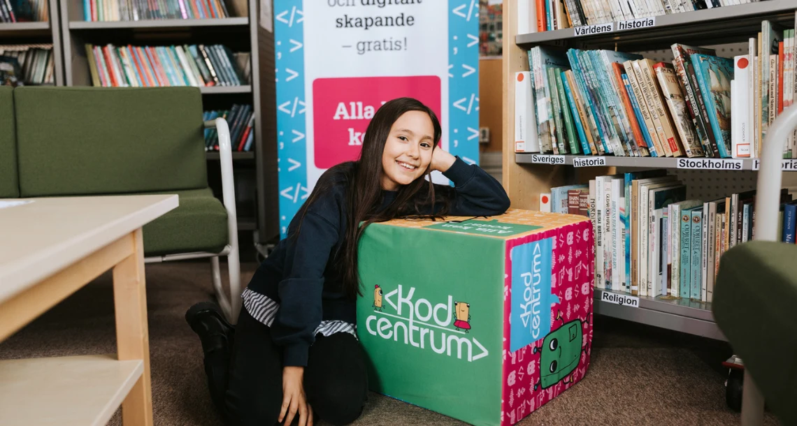 Bild på en tjej med ett bord som det står Kodcentrum på