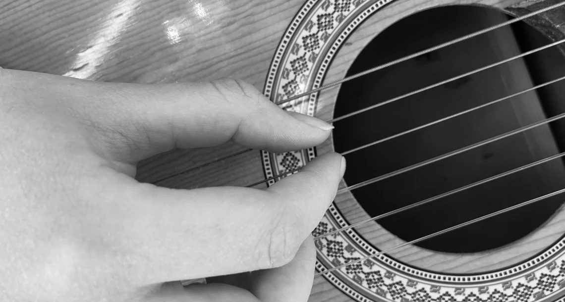 En hand som spelar gitarr i svartvitt