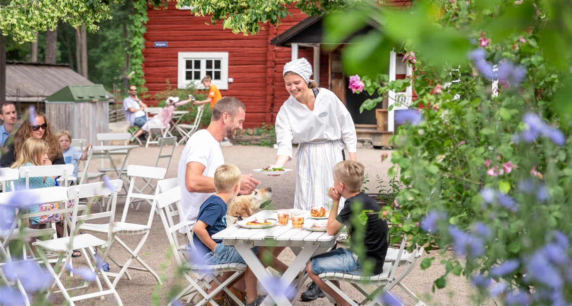 Servitris lämnar över fika till man på uteservering.