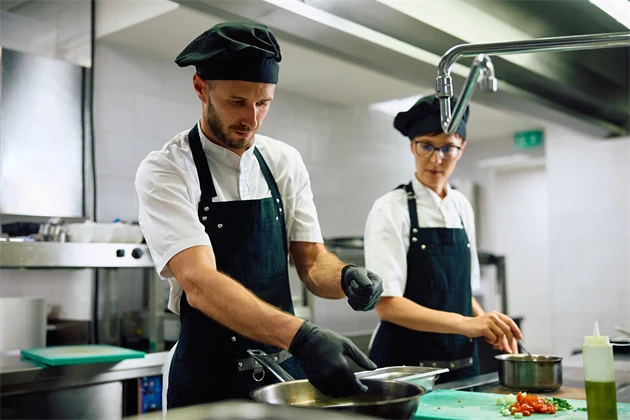 Två personer jobbar i ett restaurangkök