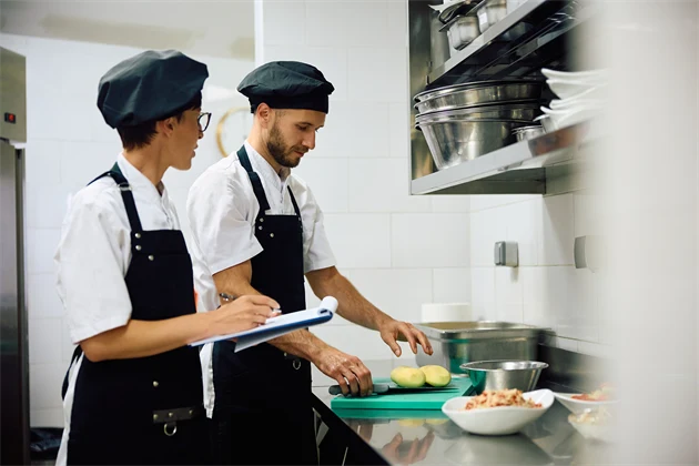Två kockar jobbar i ett restaurangkök.