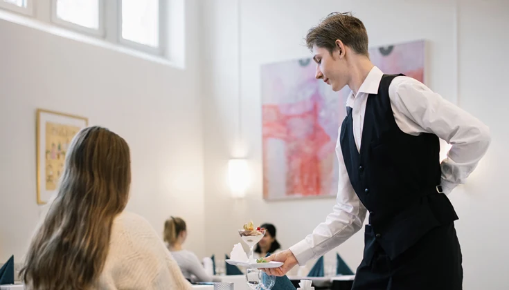 Gymnasieelev serverar en restauranggäst.