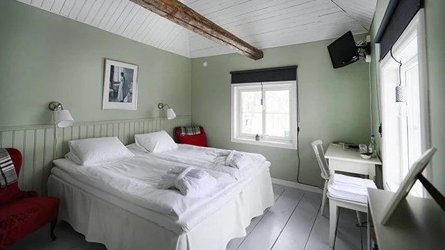 En dubbelsäng i ett rum med både trägolv och trätak och mintgröna väggar