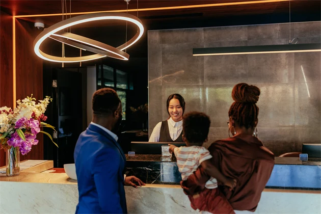 En receptionist på ett hotell hjälper en familj att checka in.