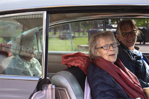 Två kvinnor i framsätet på en Cadillac, i baksätet sitter en kvinna.