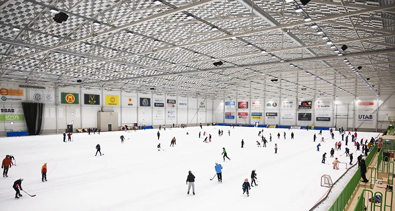 Många människor åker skridskor i en stor inomhushall.