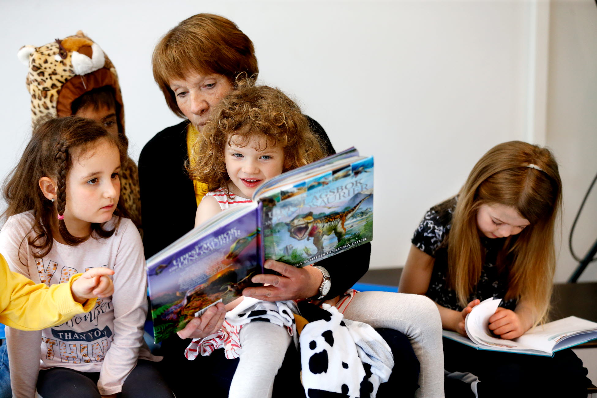 Förskollärare läser en bok för fyra förskolebarn