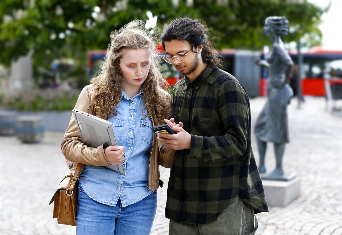 Två personer tittar ner i en telefon