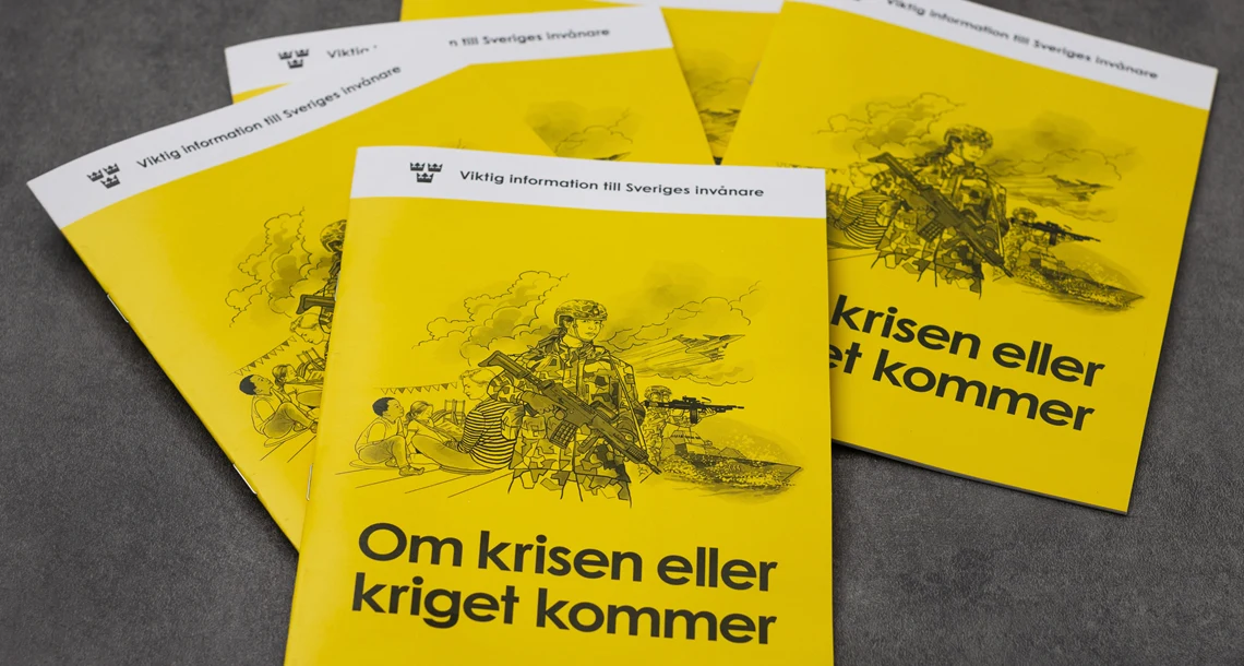 Gula broschyrer ligger på ett svart bord.