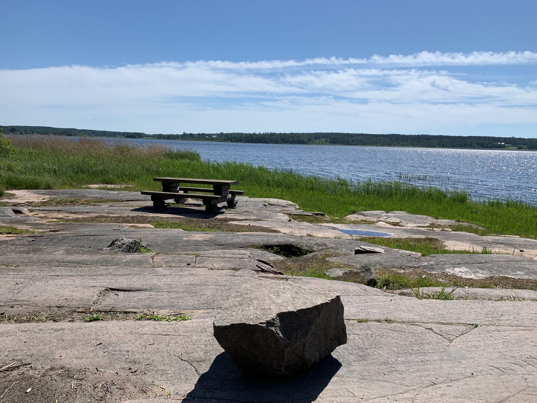 Picknickbord på klippor vid vattnet.