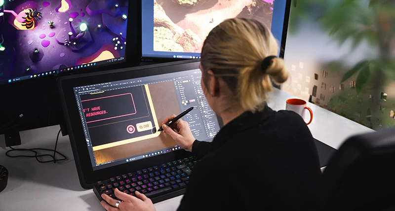 En kvinna sitter och illustrerar på en datorskärm med en penna