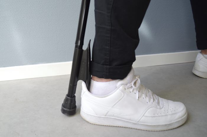 En käpp med inbyggt skohorn. I bilden används den till att sätta foten i en vit sko.