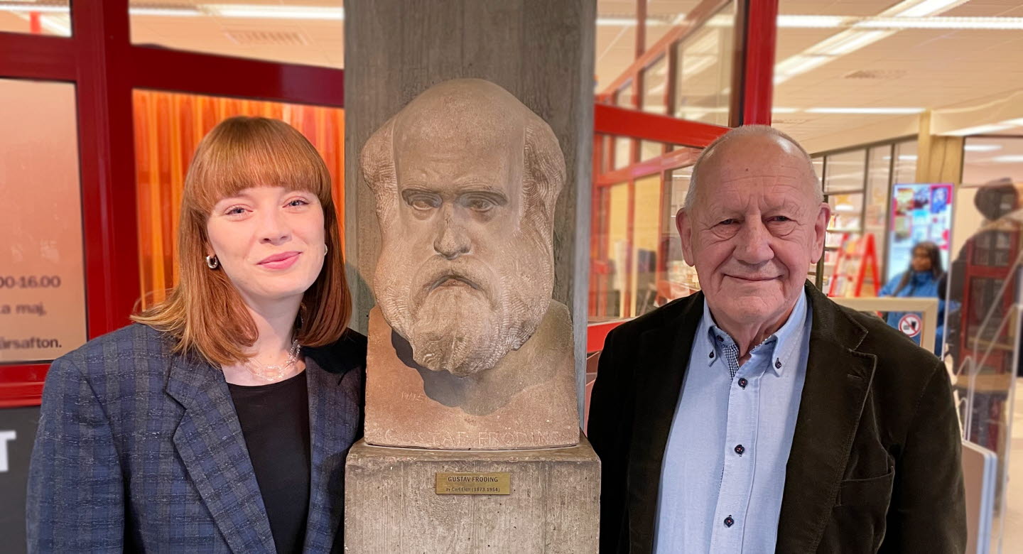 Porträttbild av Elin Lundgren och Olle Österling intill en skulptur av Gustaf Fröding