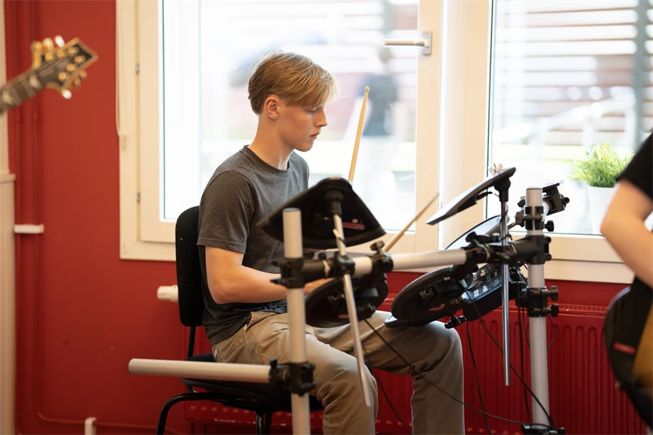 Pojke som spelar trummor i ett klassrum