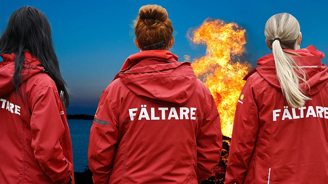 Tre fältarbetare står med ryggen mot kameran framför en majbrasa.. 