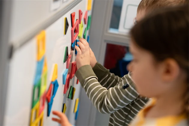 Pojke och flicka som leker med bokstäver på en vägg