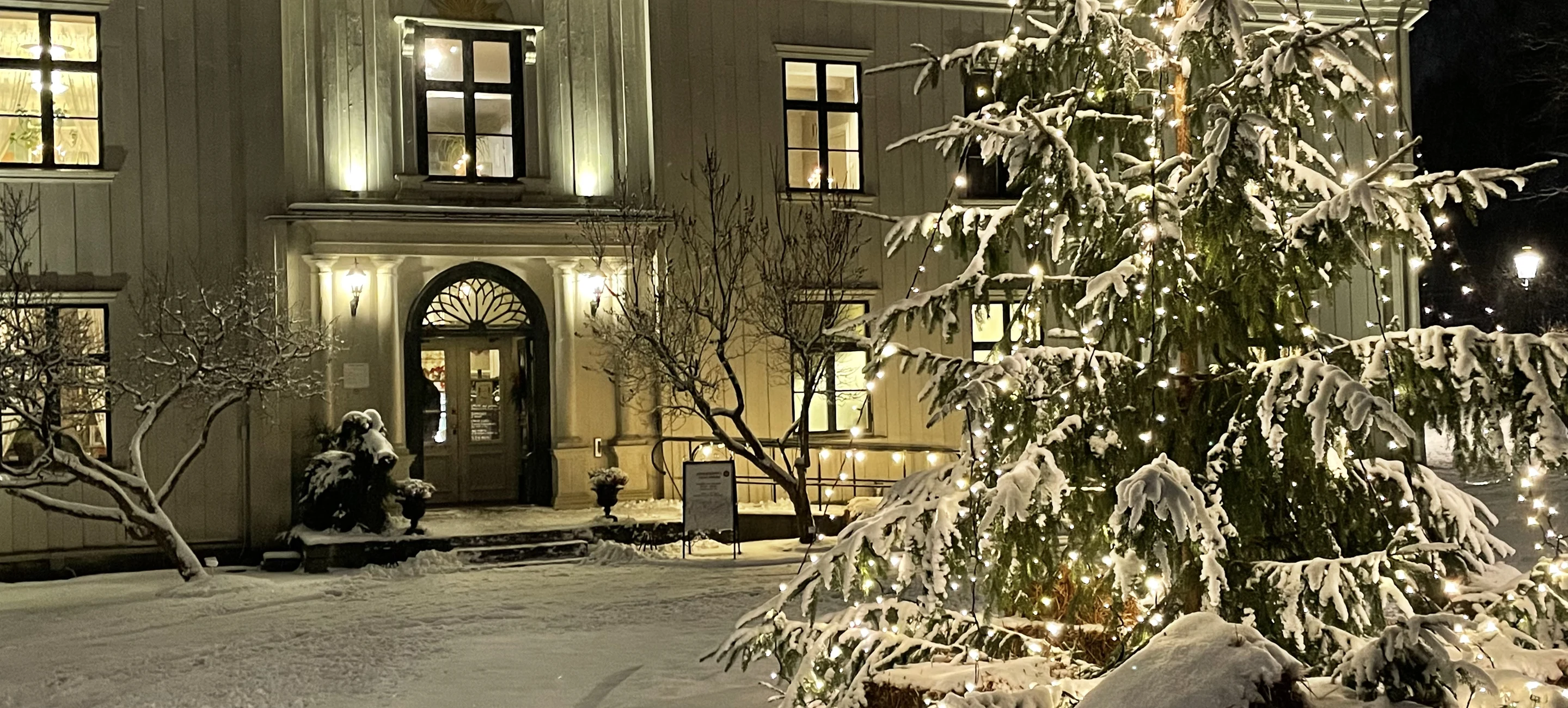 Vinterlandskap och vit snör på gran framför Alsters herrgårds vita huvudbyggnad