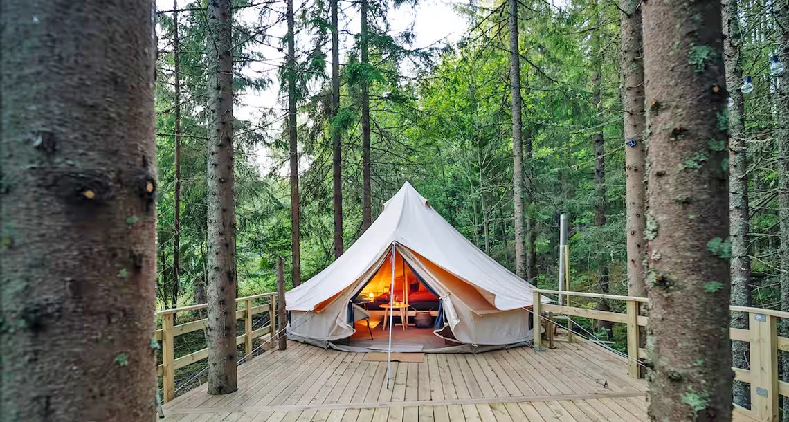 ett stort tält placerat på ett trädäck inne i skog