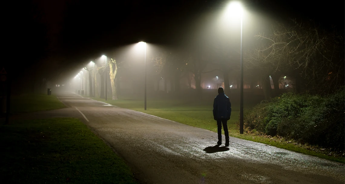 Gångväg i mörker med ljus från gatulampor