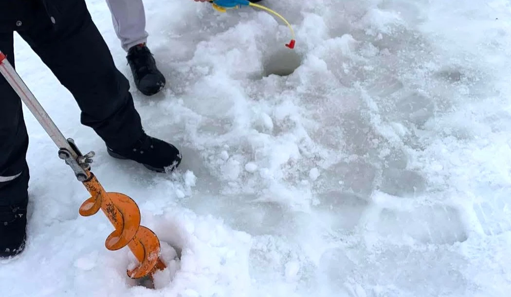 En person borrar hål i is för pimpelfiske