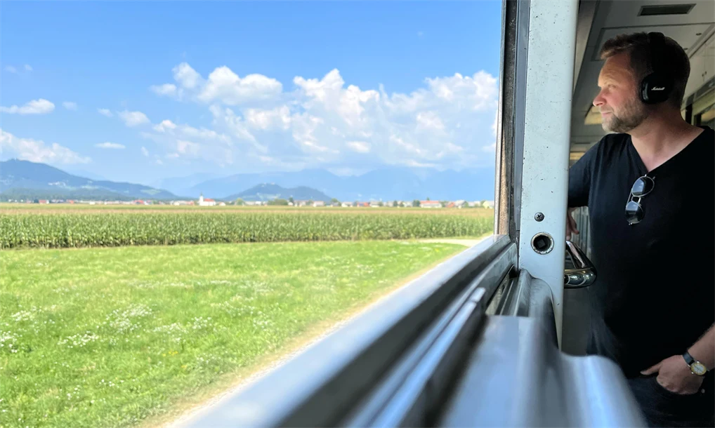 Årets vinnare av klimatpriset, Erik Nylund, åker med tåg och tittar ut genom fönstret på ett öppet grönt landskap.