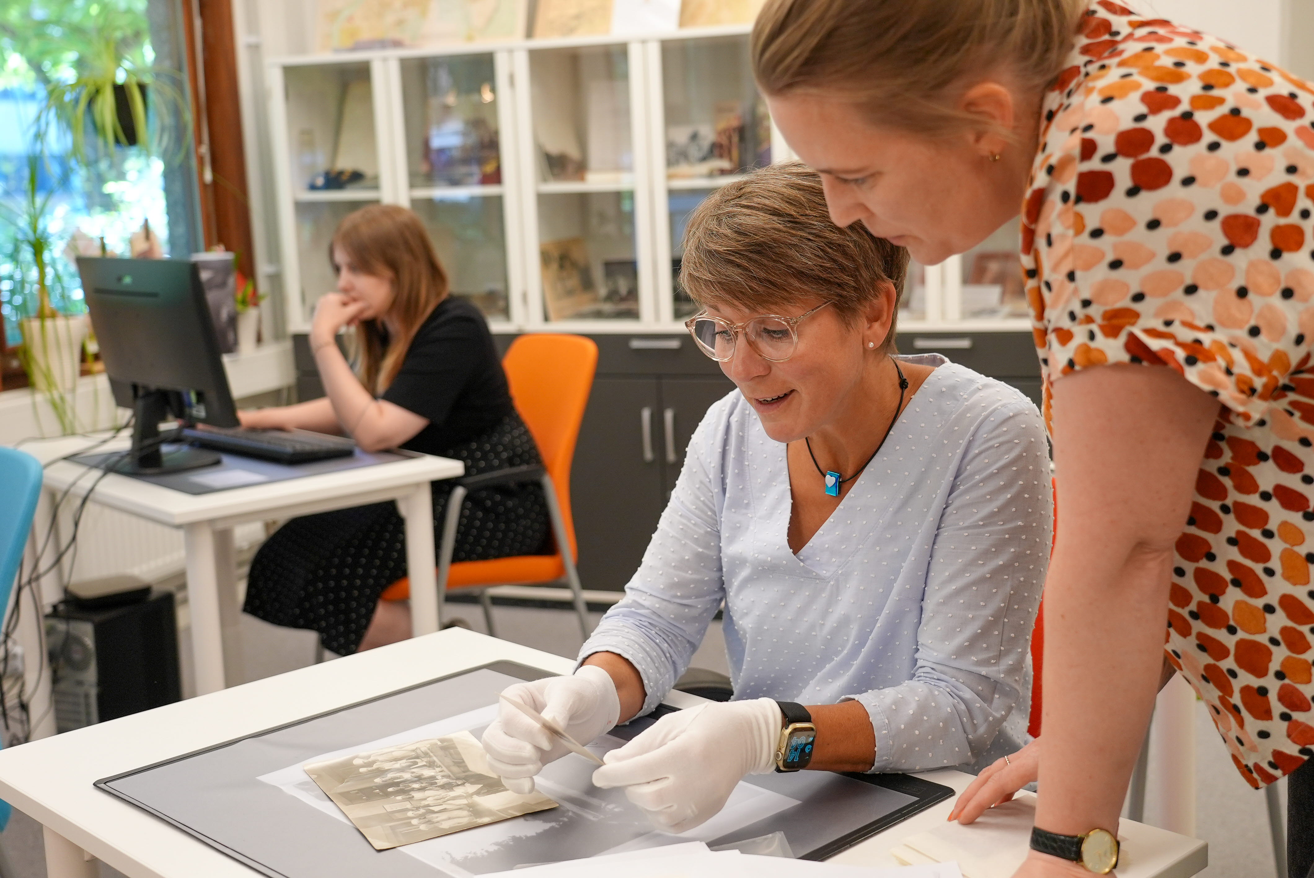 Arkivarie som pratar med en person som sitter vid en studieplats.