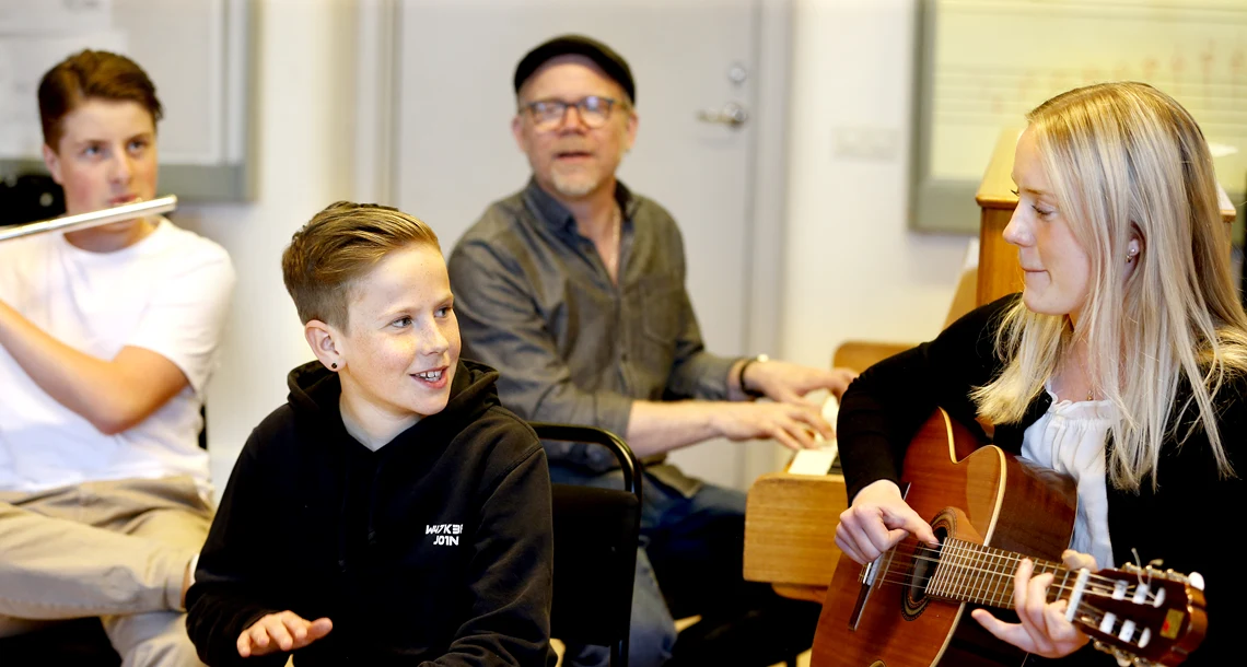 En grupp av elever och lärare som spelar piano, tvärflöjt och gitarr