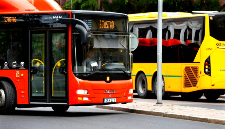 Foto av orange stadsbuss och gul länsbuss