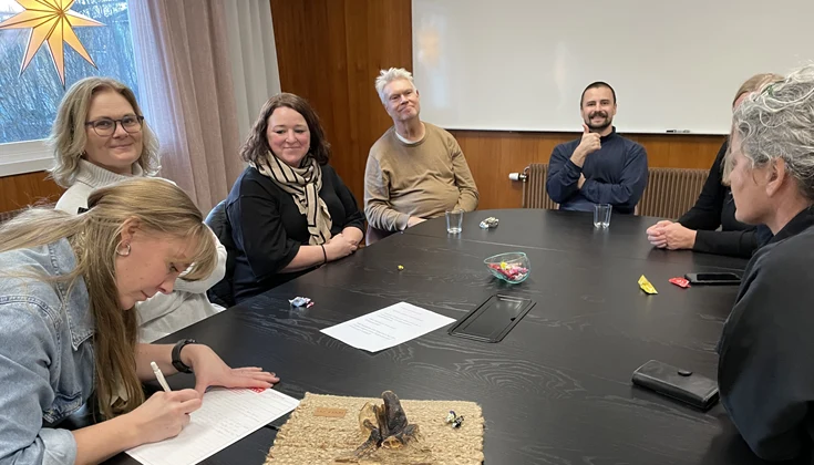 Grupp med flera personer runt ett bord. En antecknar.