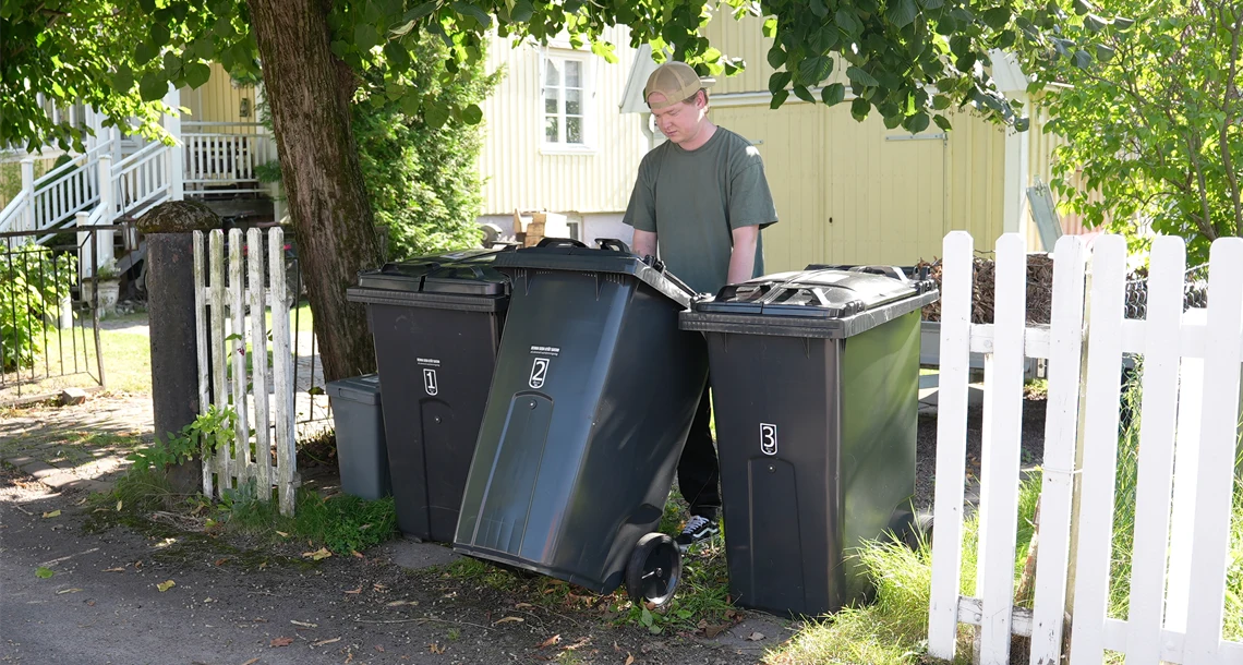 En man i 25 årsåldern drar fram sitt sopkärl till tomgräns.