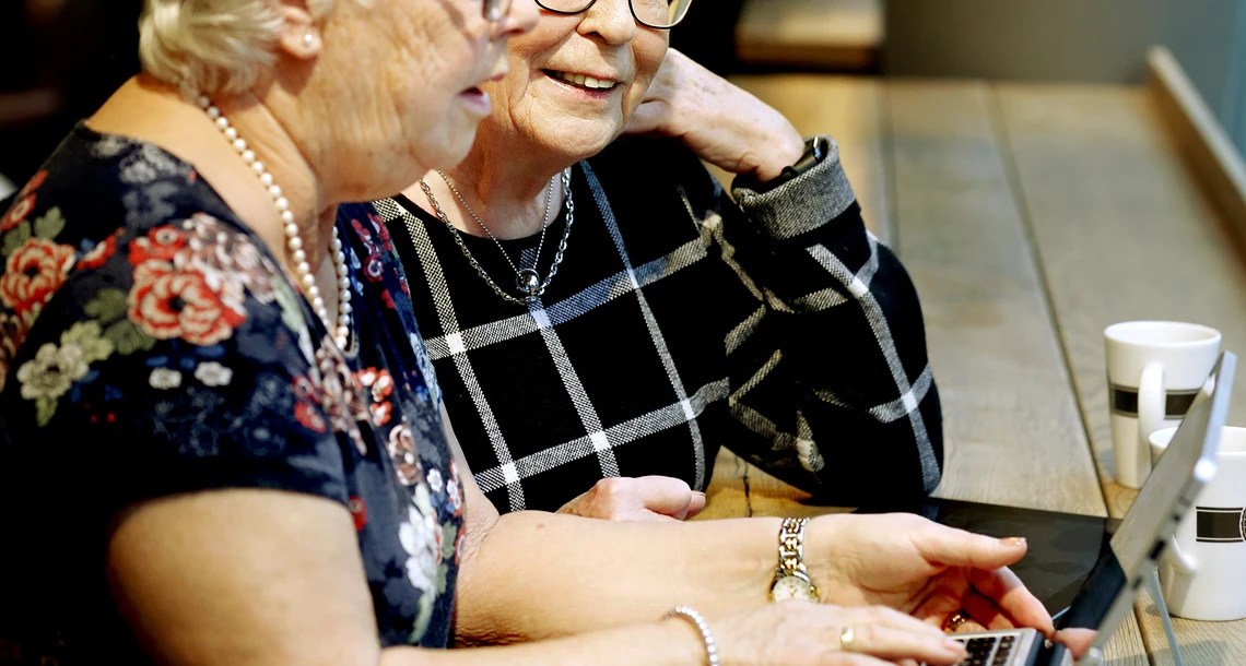 Två äldre damer med dator och surfplatta på café