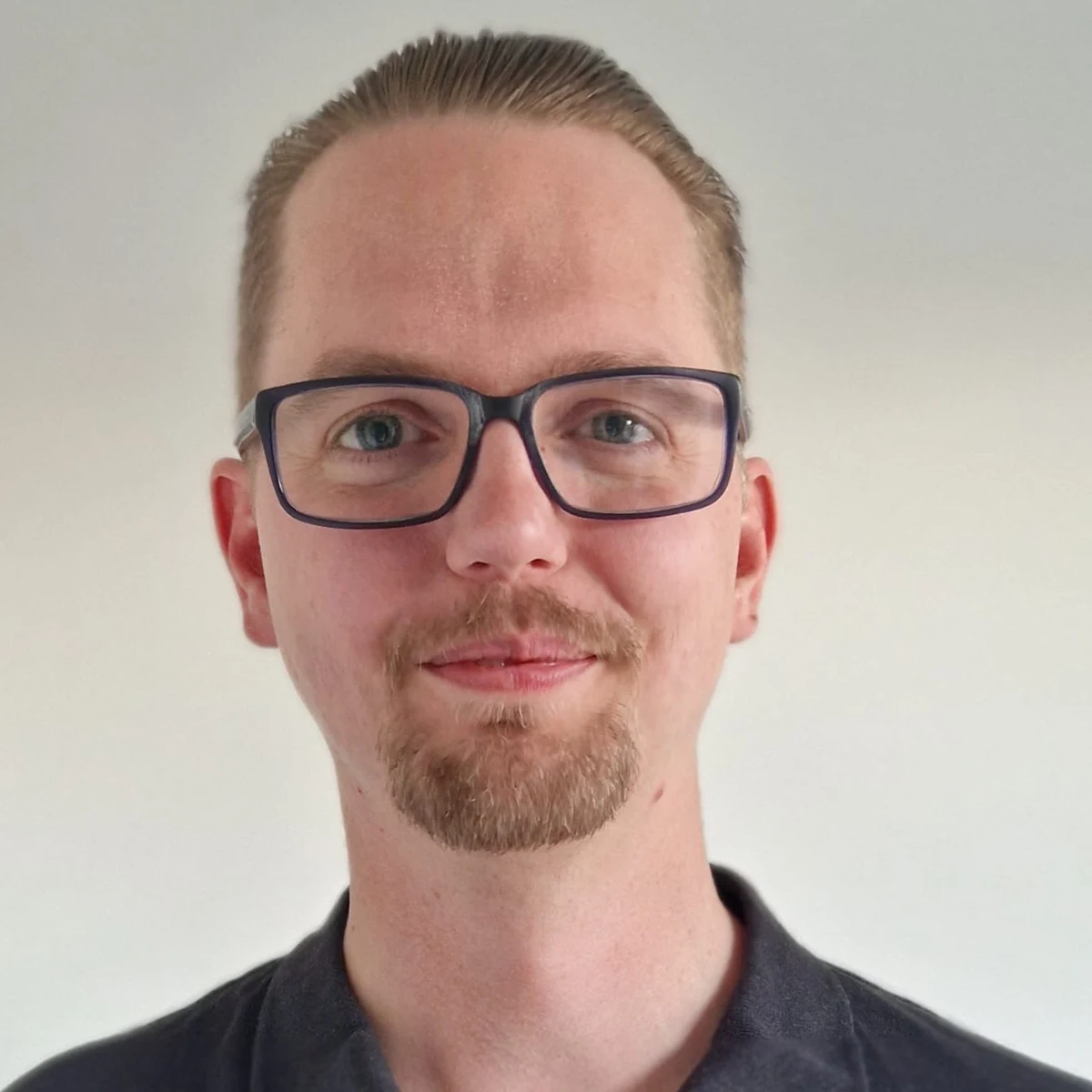 En man med glasögon ler mot kameran.