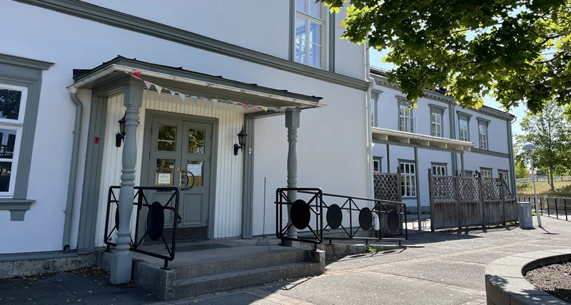 En vit byggnad med gröna fönster och dörrar