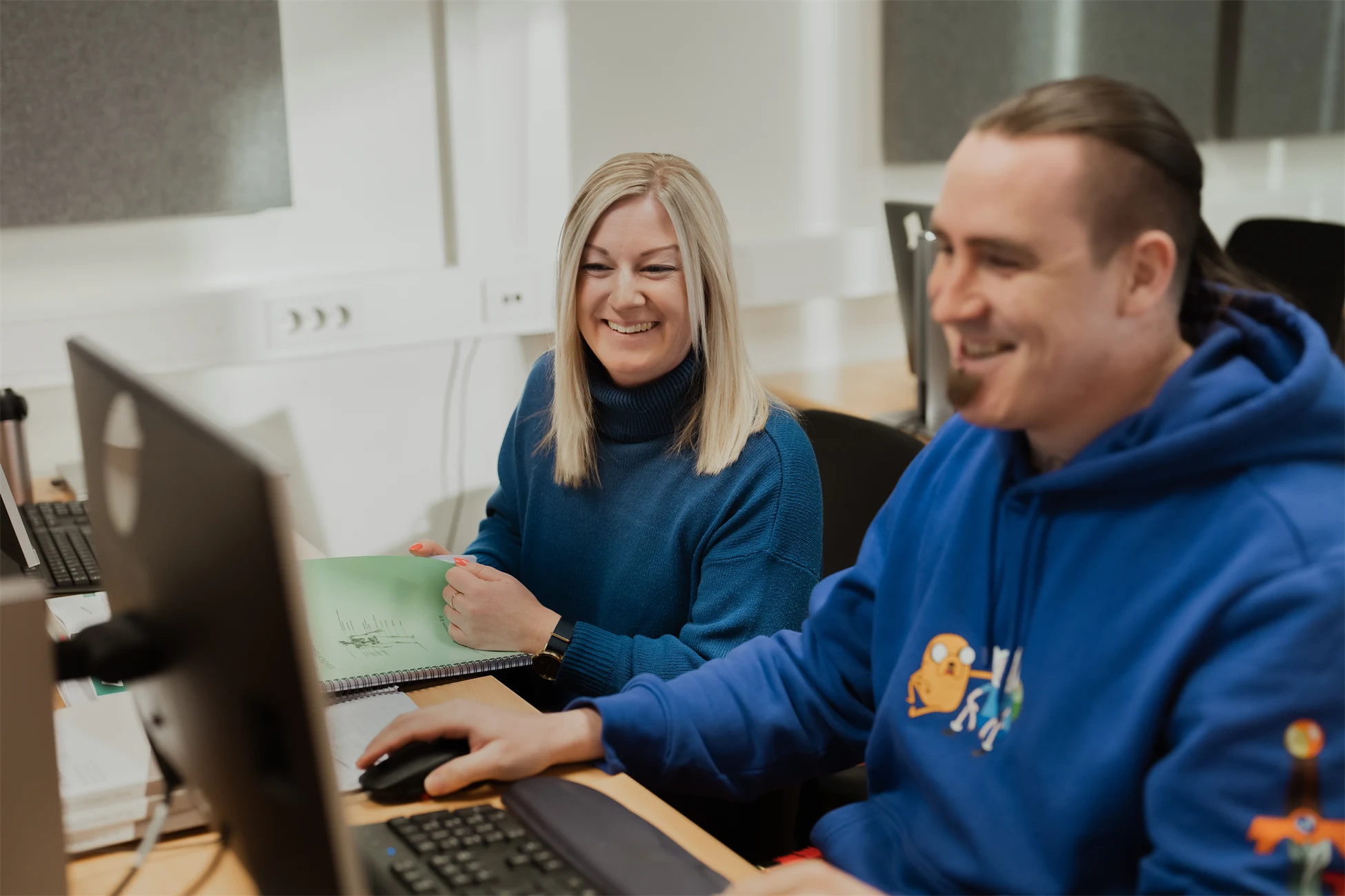 Två personer vid en dator ler.