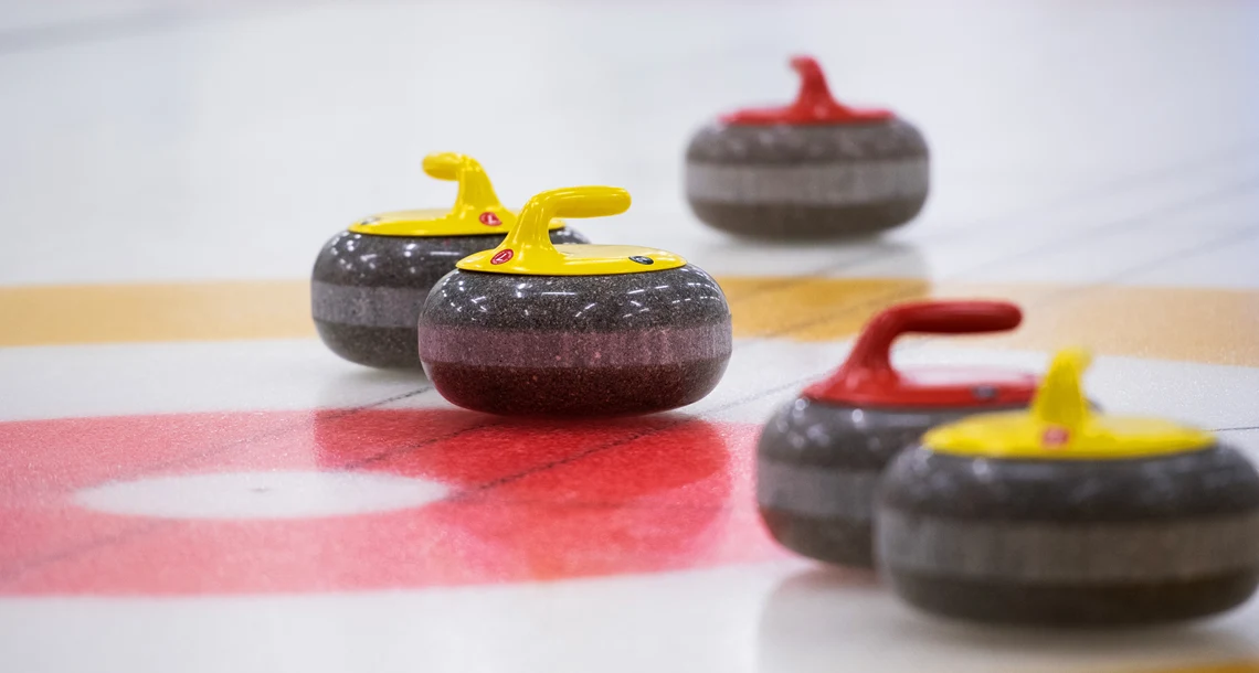 Närbild på curlingstenar på banan
