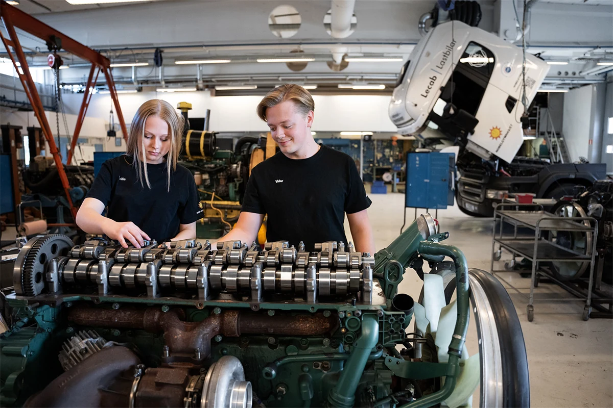 Två gymnasieelever i en verkstad tittar på en motor.
