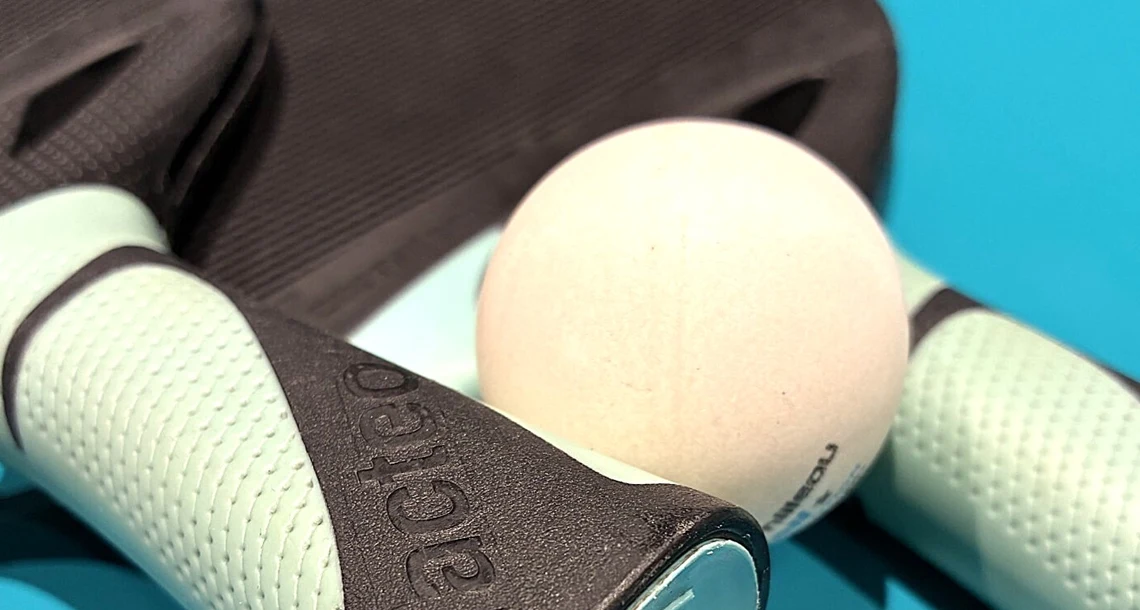 Två pingisracket och en pingisboll på ett bord