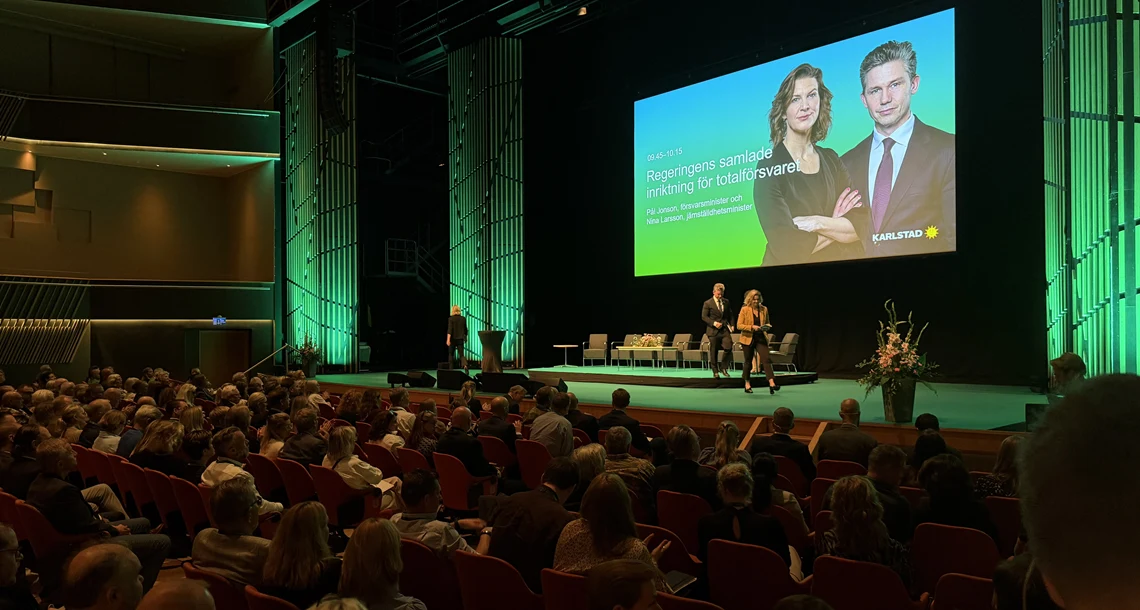 Panelsamtal på scen under Morgondagens Totalförsvar inför en stor publik.