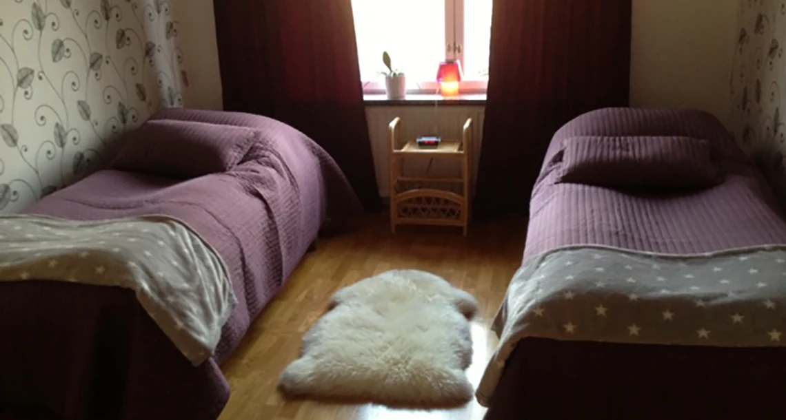 Två enkelsängar med en vit fluffig sak i mitten på golvet