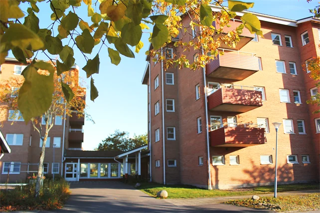 Röd tegelstensbyggnad med röda balkonger som solen lyser på.