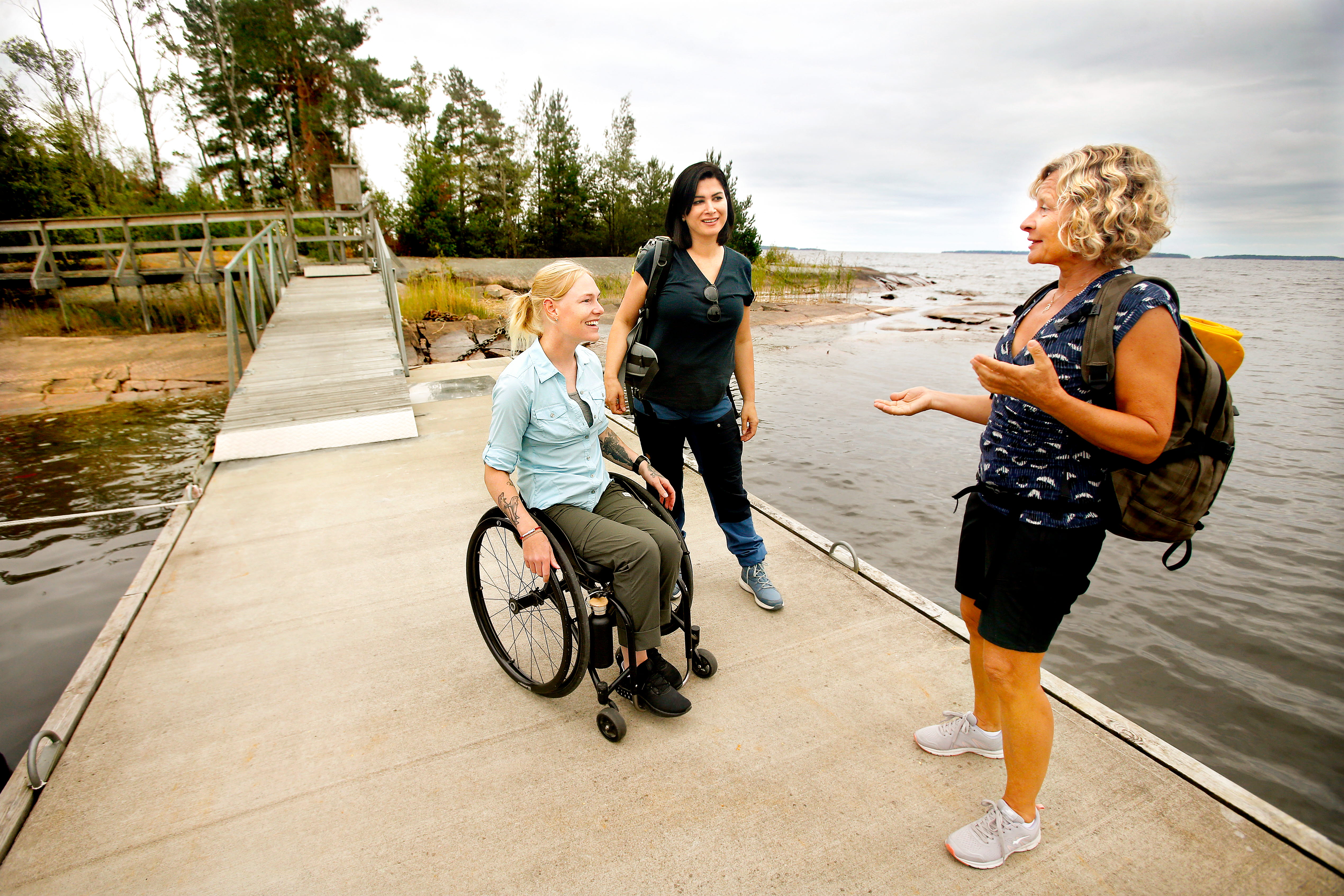 Tre kvinnor på bryggan på Jäverön. Den ena kvinnan sitter i rullstol.