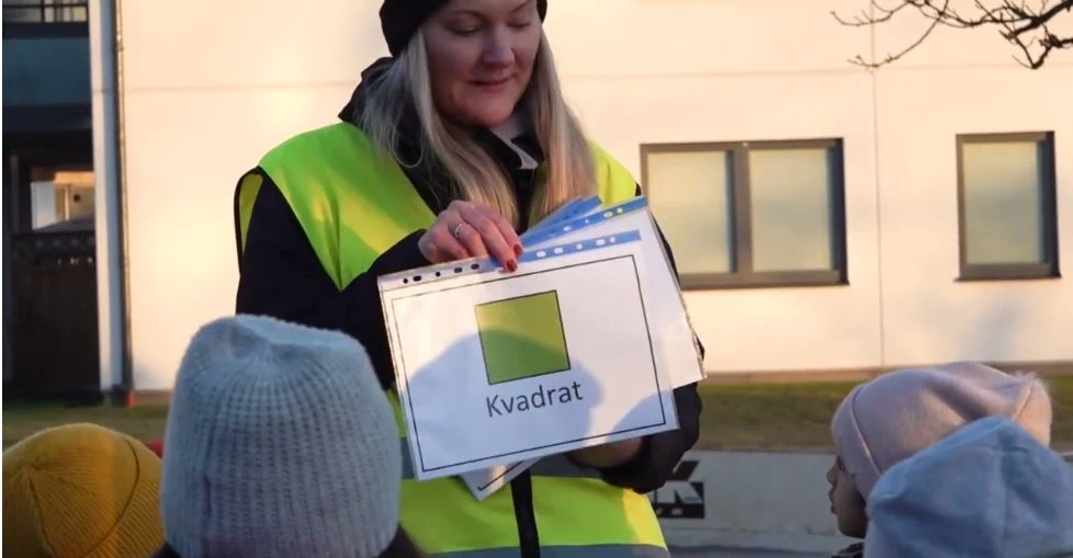 Kvinna i reflexväst som håller i en bild med en grön kvadrat
