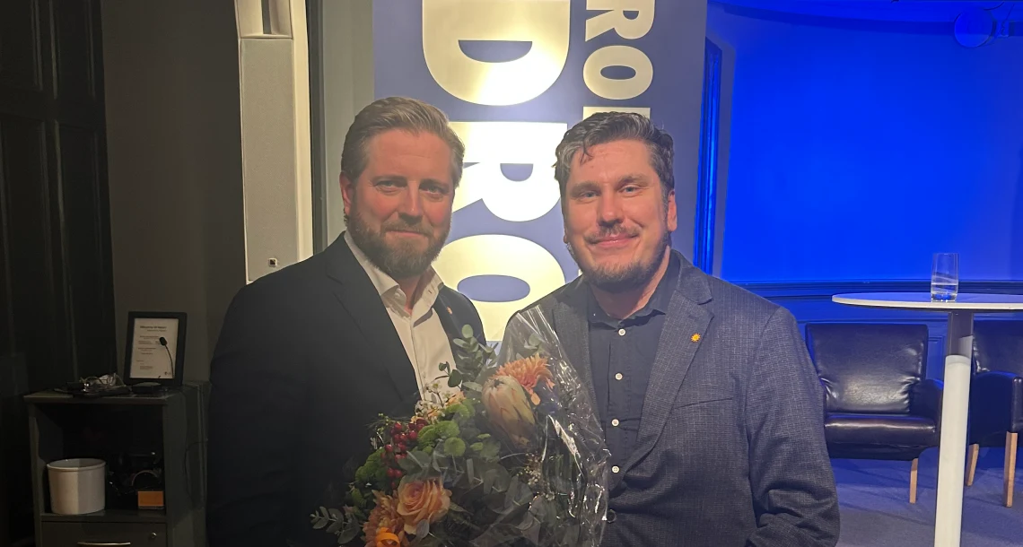 Porträtt. Två män som mottagit en utmärkelse och fått blommor.