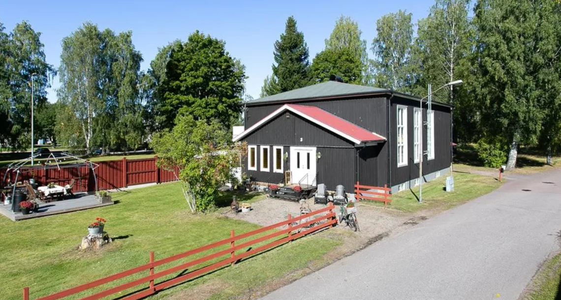 En svart byggnad med rött staket