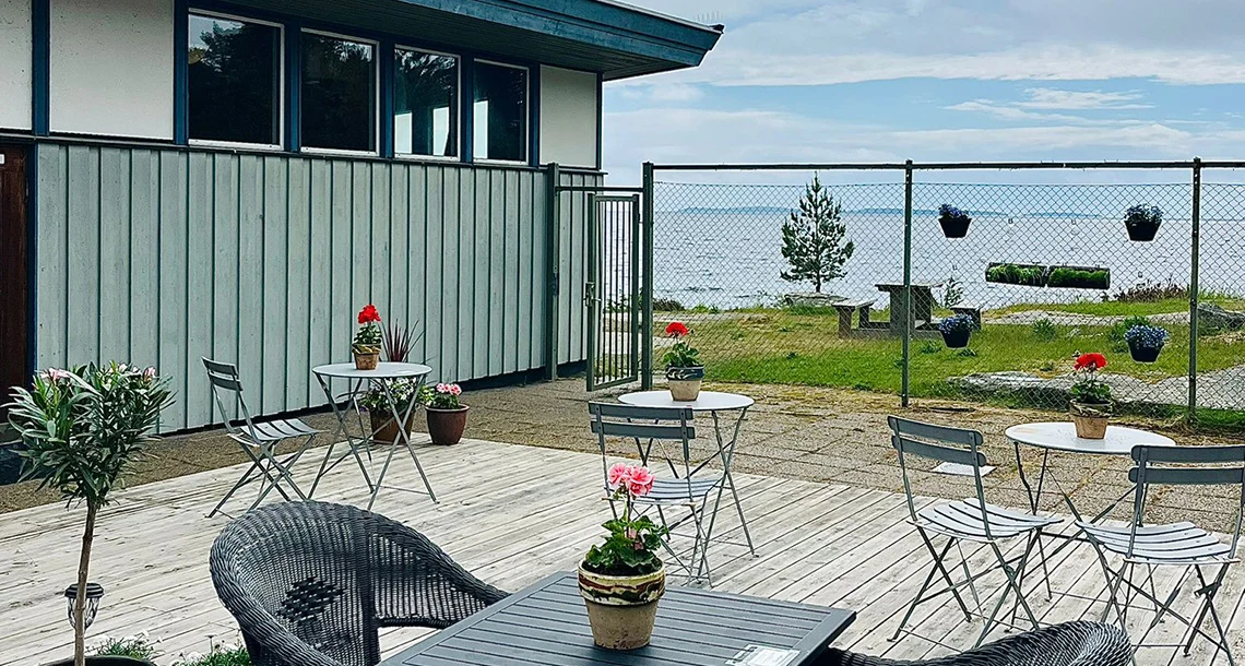 En uteservering med bord och stolar framför en husfasad